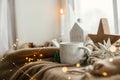 Warm cup of tea, christmas decor and lights on cozy blanket at window. Christmas Winter hygge