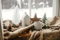 Warm cup of tea, christmas decor and lights on cozy blanket at window. Christmas Winter hygge