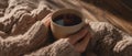 The warm cup of tea held in cozy, knitted hands on a wooden table. AI generated image Royalty Free Stock Photo
