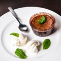 Warm dessert chocolate fondant lava cake served with vanilla ice cream balls and mint on white plate. Royalty Free Stock Photo