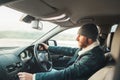 Warm dressed bearded man driving modern auto. Inside car view. Winter weather driving