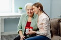 A smiling caring daughter presents a gift to her elderly mother on Women& x27;s Day. Royalty Free Stock Photo