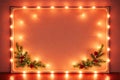 Warm Festive Blank Frame with Glowing Lights and Pine Branches on Orange Background for Christmas Royalty Free Stock Photo