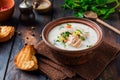 Warm Finnish creamy soup with salmon and vegetables in old ceramic bowl on old wooden background.