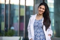 Warm, friendly portrait of a mixed ethnicity brunette female practitioner standing outside of her medical private practice