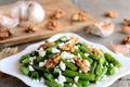 Warm green bean salad. Easy green string beans salad with cottage cheese, peeled walnuts, garlic and spices on a white plate