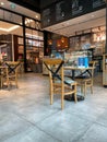 Warm interior of a coffee shop with the menu on the upper part and wooden chairs and tables