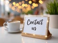 Cozy cafe table with illuminated handwritten contact us message and latte in soft background Royalty Free Stock Photo