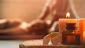 Beautiful spa composition with frangipani flower, oil flask, and candles. Blurred figures of the masseur Royalty Free Stock Photo