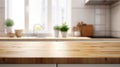 Warm kitchen interior with a sunlit wooden countertop and a blurred background featuring green plants and modern decor Royalty Free Stock Photo