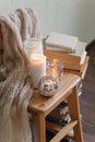 Warm knitted plaid blanket, candles, book and wooden chair - cozy home relax interior, autumn winter seasonal leisure time, hygge