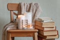 Warm knitted plaid blanket, candles, book and wooden chair - cozy home relax interior, autumn winter seasonal leisure time, hygge