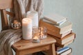 Warm knitted plaid blanket, candles, book and wooden chair - cozy home relax interior, autumn winter seasonal leisure time, hygge