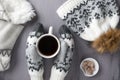 Warm knitwear: mittens, hat, scarf and cup of coffee on a gray rustic wood background. Winter cozy still life. Top view