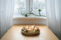 Warm light from an advent wreath with white candles, Christmas balls, cookies and moss on a table near the window on a snowy Royalty Free Stock Photo