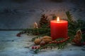 Warm light on a cold winter night from a red candle with flame, evergreen yew branches, nuts and Christmas decoration on blue gray Royalty Free Stock Photo