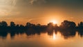 A warm orange sunset over the river. Trees and clouds reflected in the water. The ball of sun hides behind the forest Royalty Free Stock Photo