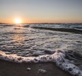The warm orange sunset sun illuminates the foamy sea waves of the Black Sea with soft light Royalty Free Stock Photo