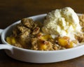 Peach cobbler with French vanilla ice cream in a small single serving dish.