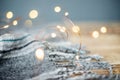 A warm plaid scarf with fringe lies.The garland is lit with lights.The concept of the Christmas and New Year holiday Royalty Free Stock Photo