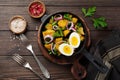 Warm potato salad with green beans, pepper, parsley, eggs and red onion in frying pan on old wooden background. Selective focus. Royalty Free Stock Photo