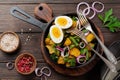 Warm potato salad with green beans, pepper, parsley, eggs and red onion in frying pan on old wooden background. Selective focus. Royalty Free Stock Photo