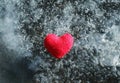 red knitted heart lying on the cold glittering ice