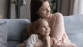 Preteen girl relax on sofa snuggle up to caring mother