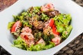 Warm salad with chicken liver, tomatoes, lettuce leaves, broccoli on wooden table. Healthy food. Royalty Free Stock Photo