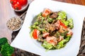 Warm salad with chicken liver, tomatoes, lettuce leaves, broccoli on wooden table. Royalty Free Stock Photo