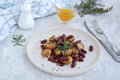 Warm salad of grilled Jerusalem artichoke and boiled red beans with olive oil and vinegar dressing on a white clay plate