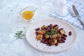 Warm salad of grilled Jerusalem artichoke and boiled red beans with olive oil and vinegar dressing on a white clay plate