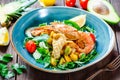 Warm salad with seafood, langoustine, mussels, shrimps, squid, scallops, mango, pineapple, avocado, arugula on wooden background