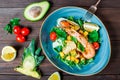 Warm salad with seafood, langoustine, mussels, shrimps, squid, scallops, mango, pineapple, avocado, arugula on wooden background