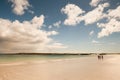 Warm sandy beach of Gurteen bay, county Galway, Ireland. Three women walking on the sand. Warm sunny day. Cloudy sky. Irish nature Royalty Free Stock Photo