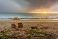 Couple of beach loungers and parasol on beach at sunset or sunrise Royalty Free Stock Photo