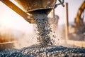 Close-up of gravel or small stones being poured from a large container at a construction site during golden hour Royalty Free Stock Photo
