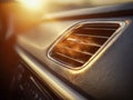Warm sunlight illuminating the textured surface of a car dashboard highlighting the air vent with soft focused background and Royalty Free Stock Photo