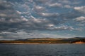 Warm sunset with clouds on Lake Baikal, gold green coast with hills and mountains Royalty Free Stock Photo