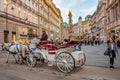 Warm sunset over busy with tourists famous Graben shopping street near Stephans square Stephansplatz with a horse drawn carriage