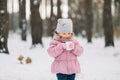 Warm winter photo. Close-up shot of a pretty cute little child girl wearing pink coat and gray cap, holding a cup of hot Royalty Free Stock Photo