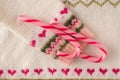 Warm woolen Christmas sweater sleeve with red hearts pattern and candy cane sweets. Close up. Flat lay. Funny Christmas concept