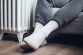 Warming Feet on White Radiator, Man Warms his Feet at Home, Cold Winter, Expensive Electricity Saving Concept