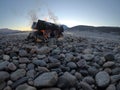 Warming fire on cold rocky river shore in early winter