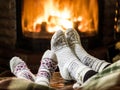 Warming and relaxing near fireplace. Woman and child feet in front of fire