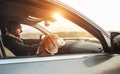 Warmly dressed man enjoying the modern car driving with his beagle dog sitting on the co-driver passenger seat. Traveling with pe