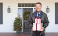 Warmly Dressed Man Holding Gifts Standing on Christmas Decorated Front Porch Royalty Free Stock Photo