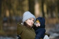 Warmly dressed mom and baby are walking along the street. Mom holds a baby in her arms in winter. Mom and son outdoors in winter. Royalty Free Stock Photo