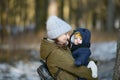 Warmly dressed mom and baby are walking along the street. Mom holds a baby in her arms in winter. Mom and son outdoors in winter. Royalty Free Stock Photo