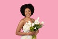 Warmly smiling young woman with natural afro hair lovingly holding a bouquet Royalty Free Stock Photo